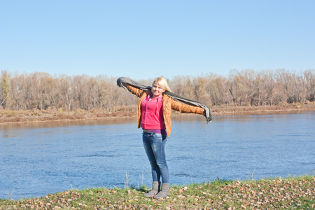 Blonde young girl by the river. Autumn Sunny dayの写真素材
