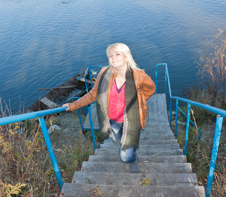Blonde young girl by the river. Autumn Sunny dayの写真素材