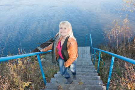 Blonde young girl by the river. Autumn Sunny dayの写真素材