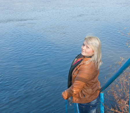 Blonde young girl by the river. Autumn Sunny dayの写真素材