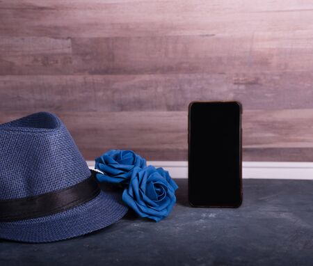 Men's accessory gift for Father's Day or anniversary on wood table background, blue roses, hat and...