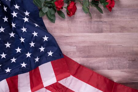 Vintage red, white, and blue American flag for Memorial day, 4th of July  or Veteran's day with red roses on a wood background.の写真素材