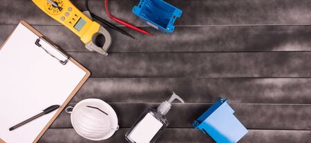 Professional electrician emergency and repair services. face mask, hands sanitizer, multimeter and space for text in a wood background.  Social distancing.の写真素材