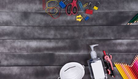 Back to school concept.Real life 2020. during the Corona-virus Disease Pandemic.  School items supplies, face mask, hands sanitizer and space for text in a wood background.の写真素材