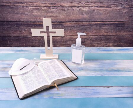Sanctuary of a church with wood cross, face mask, hand sanitizer and bible on vintage wood...