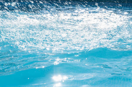 Splashing shiny blue water in a swimming pool.Selective focus.