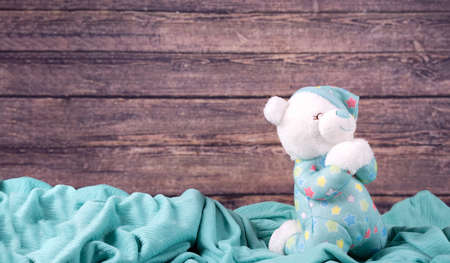 Cute white teddy bear pray on blue fabric background. New Born,communion ,confirmation or baptism Greeting Card. copy space.の写真素材
