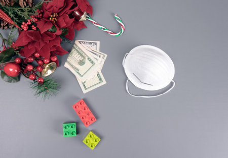 Xmas and New Year greeting card with American dollars, toys, and face mask over Christmas decoration composition on wood background. 
Virus money concept. copy space.の写真素材