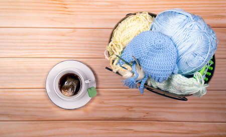Skeins of wool, knitting needles and hot cup of coffee on wooden background with Space for text.の写真素材