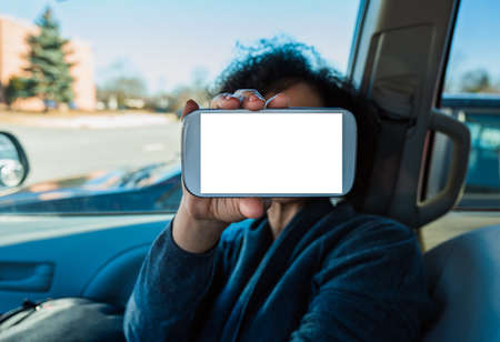 Phone application mock-up inside car. Female hand holding mobile white empty screen. Copy space text. Selective focus.の写真素材