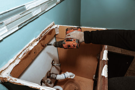 Handyman replacing an old bathroom cabinet. Plumbing repair service, assembling and install concept.