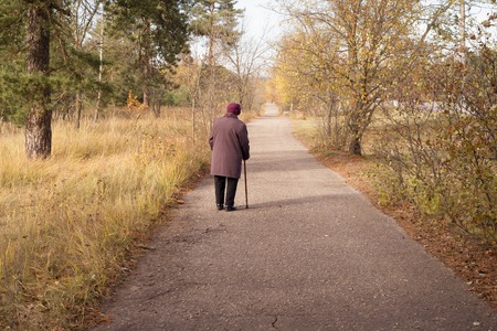 Lonely elderly woman walks in autumn parkの写真素材