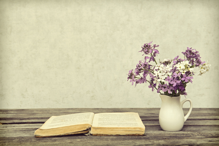 Vase with the flowers and the open book on a wooden background, style a vintageの写真素材