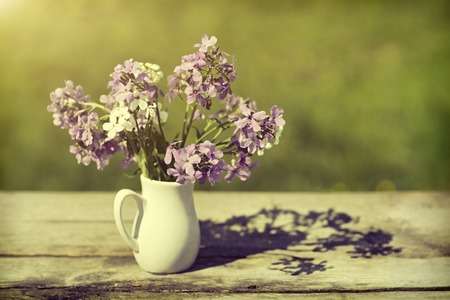 Violet flowers in a vase on a wooden table, style a vintageの写真素材
