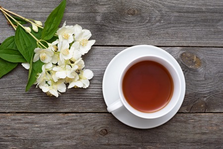 Cup of tea and jasmine on an old wooden table. Tea in white cup close up.の写真素材