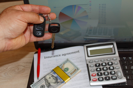 Insurance policy and key from the car. Insurance concept. Car insurance form with car keys, pen, much dollars, Laptop and calculatorの写真素材