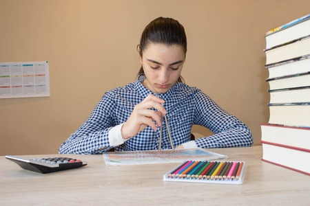 Young Girl is working with atlas at the wood table. Education and school concept - little student girl with many booksの写真素材
