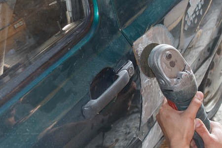 Mechanic worker repairman fixing by sanding polishing car body and preparing for painting at station service. Worker repairing car bodyの写真素材