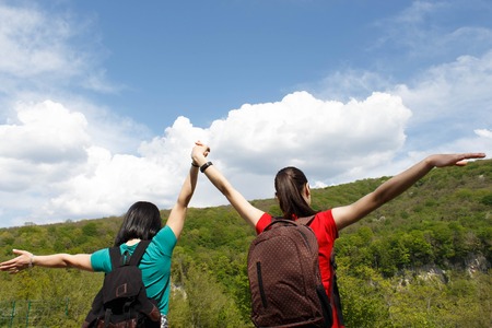 Young hiker girls with backpack enjoying and looking to the sky with clouds. Active hikers