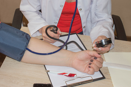 Doctor checking blood pressure of a patient, he is measuring pulses with a sphygmomanometer....