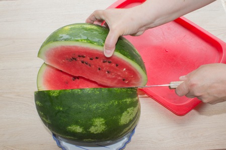 Female cutting watermelon. Vegetables and fruits, cooking process. woman with watermelon and a knife in handの写真素材