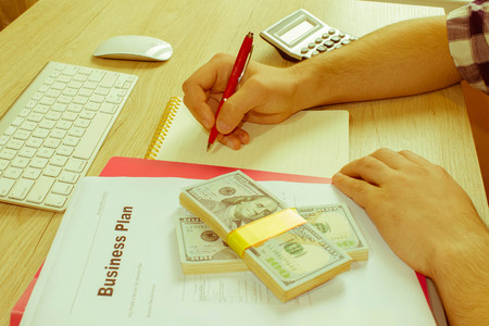 Man, taking notes. Man with dollars, Cash on the table. Profits, savings. Stack of dollars. Success, motivation, financial flows, wealth. Stack of dollars. - Retro colorの写真素材