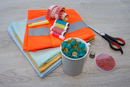 Sewing tools and sewing kit on wooden textured background. Sewing kit. Thread, needles and cloth....