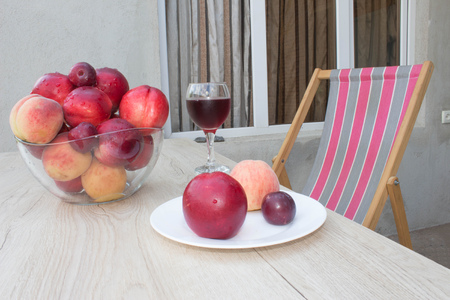 Fresh juicy peaches, nectarine and plums on the kitchen table. A glass of red wineの写真素材