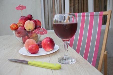 Fresh juicy peaches, nectarine and plums on the kitchen table. A glass of red wineの写真素材