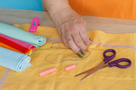 Woman hands sewing yellow dress from textile. needlework and hand quilting - tailor hands sew yellow with the use of needlesの写真素材