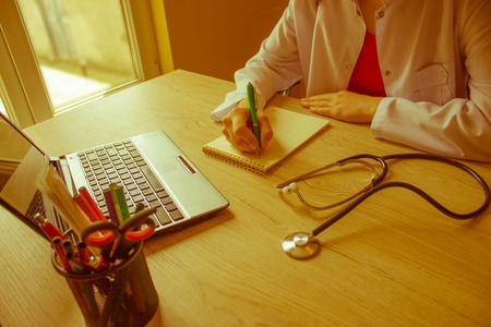 Doctor sitting at the desk near window. Healthcare and medical concept. Medicine doctor's working place - Retro colorの写真素材