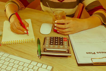 Young woman working in office, sitting at desk, using computer. Business executive woman at workplace. Businesswoman Calculating Tax At Desk In Office  - Retro colorの写真素材