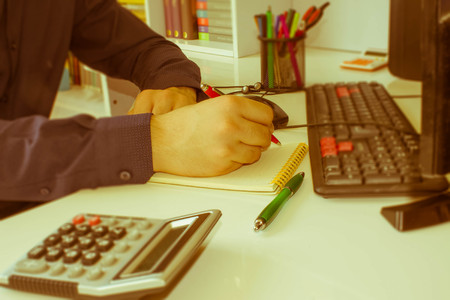 closeup pen on paperwork accounts with man use computer to save data in background. accounting concept. Man hand with pen, calculator and computer on wooden table - Retro colorの写真素材