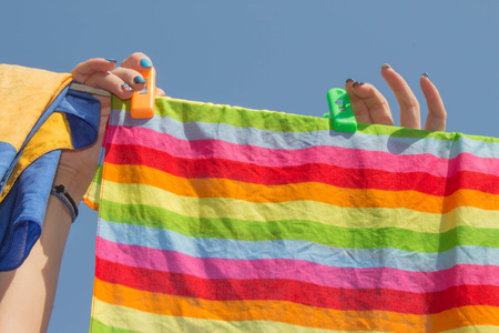 woman hanging clothes on the line outdoors. A woman hung washed laundry outdoors. Girl drying laundry on a clothes line in the sun in the outdoorの写真素材