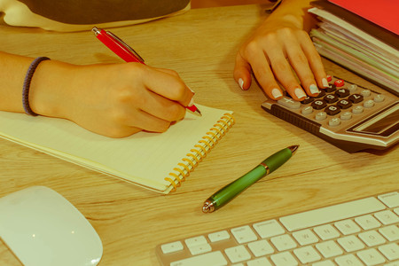 Young woman working in office, sitting at desk, using computer. Business executive woman at workplace. Businesswoman Calculating Tax At Desk In Office  - Retro colorの写真素材