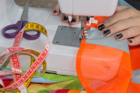Woman hand on sewing machine.Dressmaker work on the sewing machine. Hobby sewing fabric as a small...