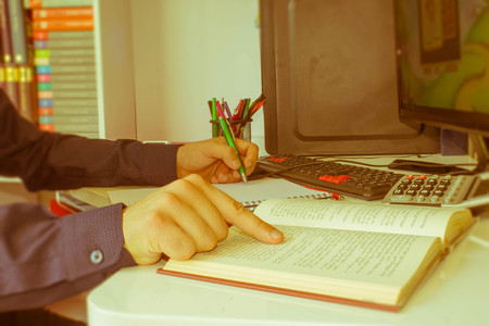 closeup pen on paperwork accounts with man use computer to save data in background. accounting concept. Man hand with pen, calculator and computer on wooden table - Retro colorの写真素材