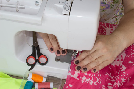 processes of sewing on the sewing machine sew women's hands sewing machine. Female tailor threading leather material on sewing machine. designer making a garment in her workplaceの写真素材