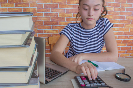 Student, Young Girl write in notebook between books. Girl working on his homework. young attractive student Girl studying lessonsの写真素材