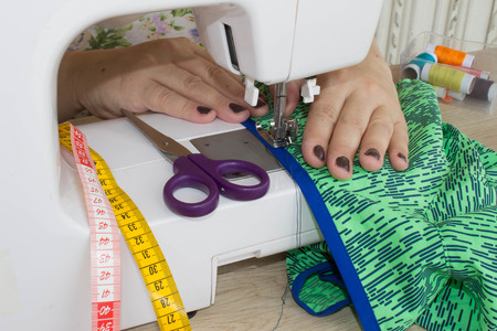 designer making a garment in her workplace. seamstress sews clothes. Workplace of tailor - sewing...
