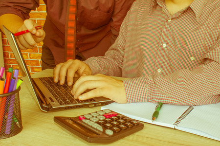 Corporate businessman working at office desk, he is using a calculator, point of view shot. Business people communicating - Retro colorの写真素材