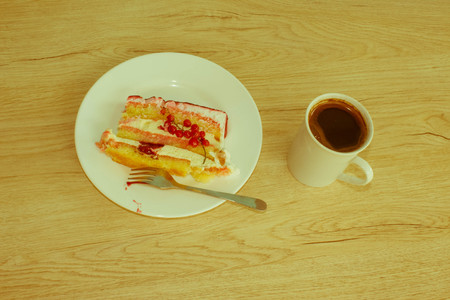 A cup of coffee and cake on wooden background. Fruit Cake with fresh red currant on the plate - Retro colorの写真素材