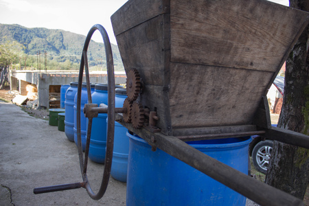 Vintage roller crusher for grapes and wine barrels. Wine concept