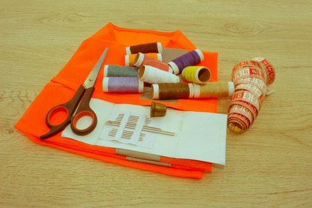 Sewing tools and sewing kit on wooden textured background. Sewing kit. Thread, needles and cloth
