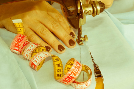 processes of sewing on the sewing machine sew women's hands sewing machine. Female tailor threading leather material on sewing machineの写真素材