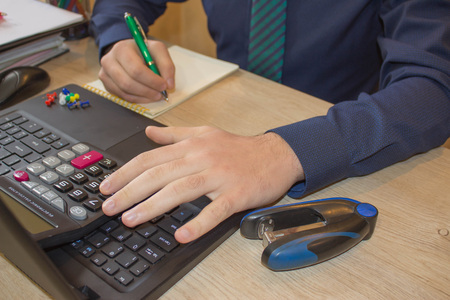 Pen on paperwork accounts with man use computer to save data in background. Man hand with pen, calculator and computer on wooden table. saving money or insurance concept. top startup business ideasの写真素材