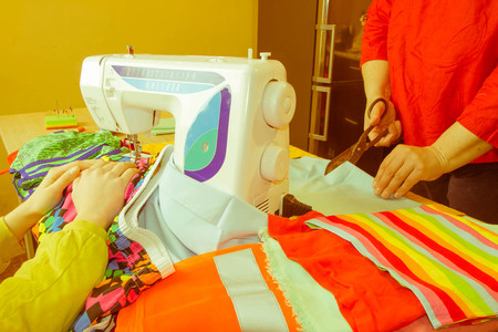pattern, scissors, tape measure, and a sewing machine. Workplace of seamstress. Dressmaker cuts dress detail on the sketch lines. Garment industry, tailoring conceptの写真素材