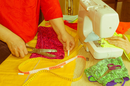 Female fashion designer working at studio with pattern cuttings and sketches. Garment industry, tailoring concept. woman seamstress sitting and sews on sewing machineの写真素材