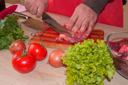 Butcher cutting meat on kitchen. Man in the kitchen cutting a piece of meat. Preparing meal
