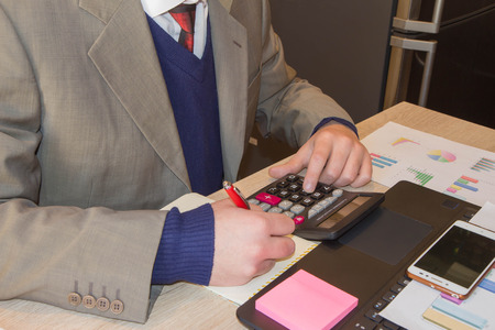 Businessman using a calculator to calculate the numbers. Businessman calculate finance and thinking about problem in home office. business male hands in officeの写真素材